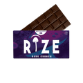 A Rize 12G Mushroom Chocolate Bar is partially unwrapped from a purple and blue wrapper labeled “RIZE Dark Crunch,” featuring a psychedelic mushroom graphic, “MEGADOSE 12G,” and a vegan symbol.